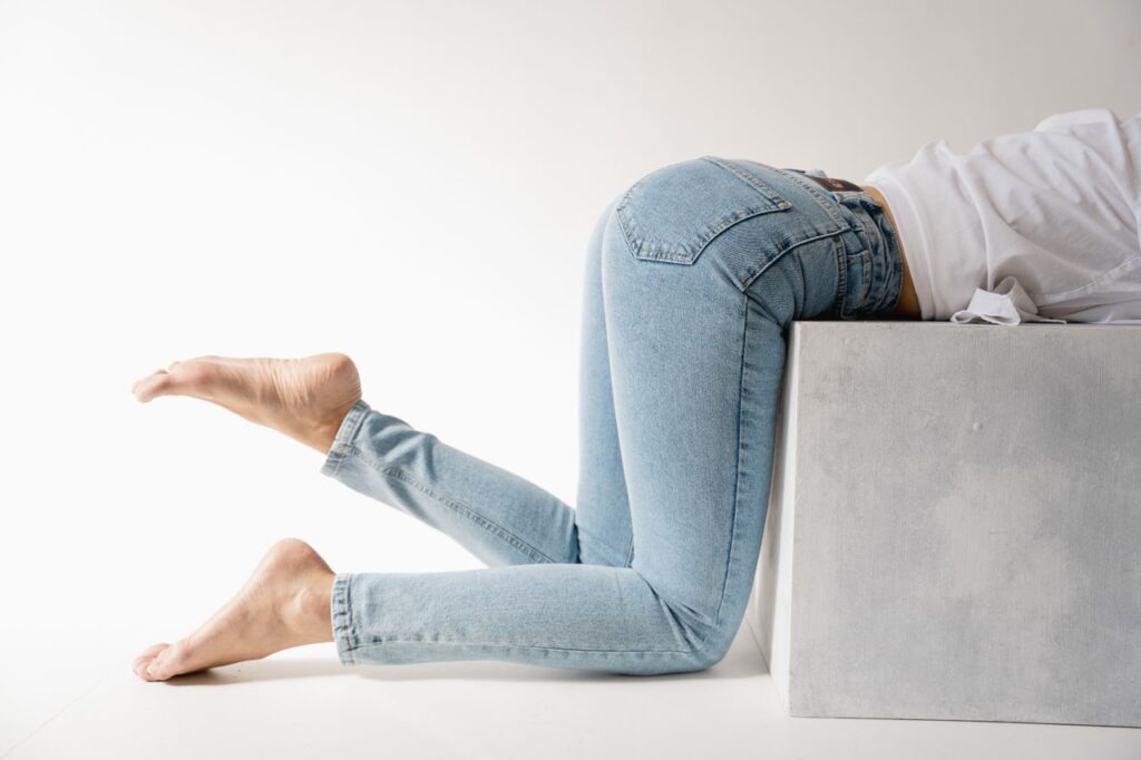 Casual fashion shoot featuring denim jeans and white tee in a minimalist studio setting.