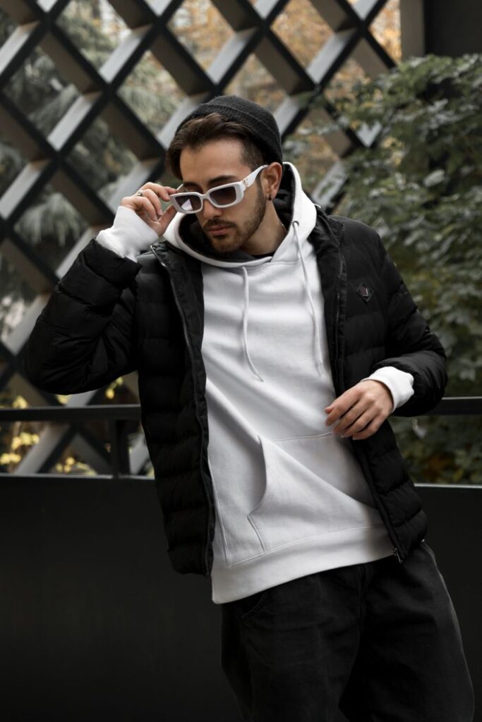 Stylish man in urban setting wearing a jacket and sunglasses.