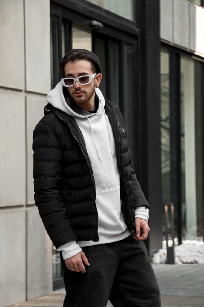 Modern urban fashion with a stylish man in sunglasses, hoodie, and puffer jacket.