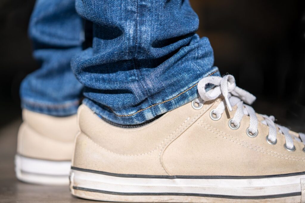 Close-up of beige canvas sneakers and blue denim jeans, showcasing urban casual fashion.
