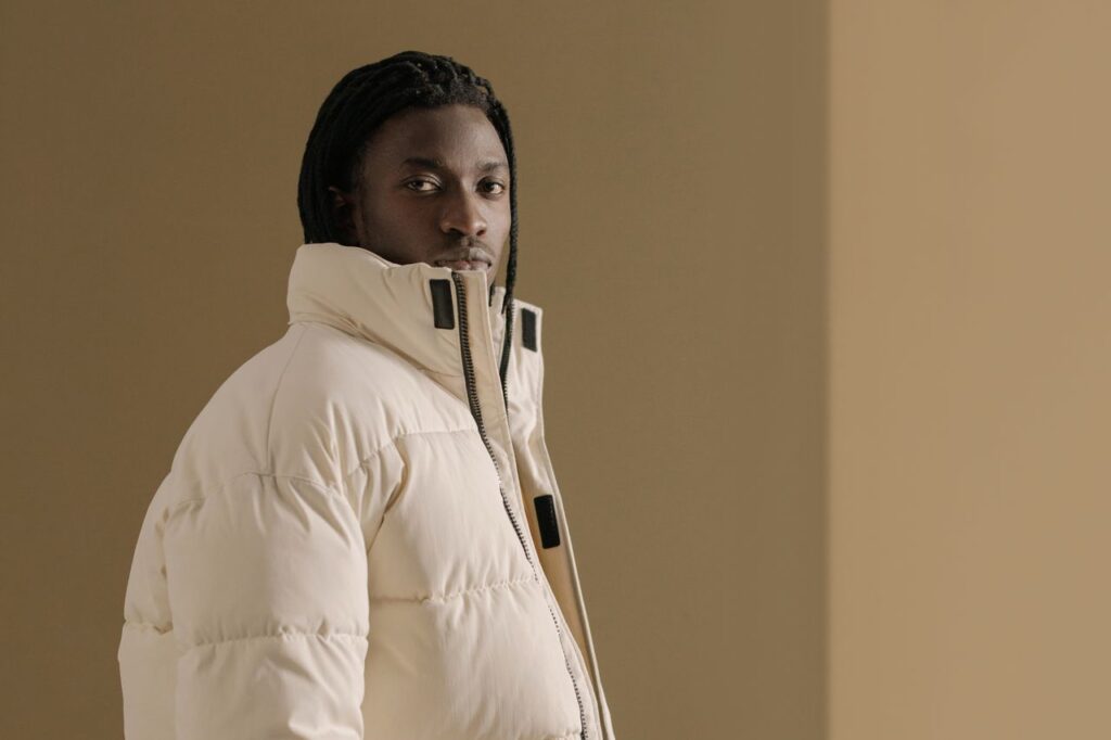 Portrait of a man in a beige winter coat with a neutral background, exuding style and confidence.